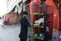 パキスタンで閉鎖されたペットショップの外に置かれた折の中の猫にえさを与える店員 (2) - コピー